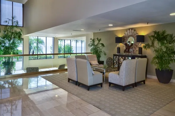 a living room with couches painting on the wall and potted plants