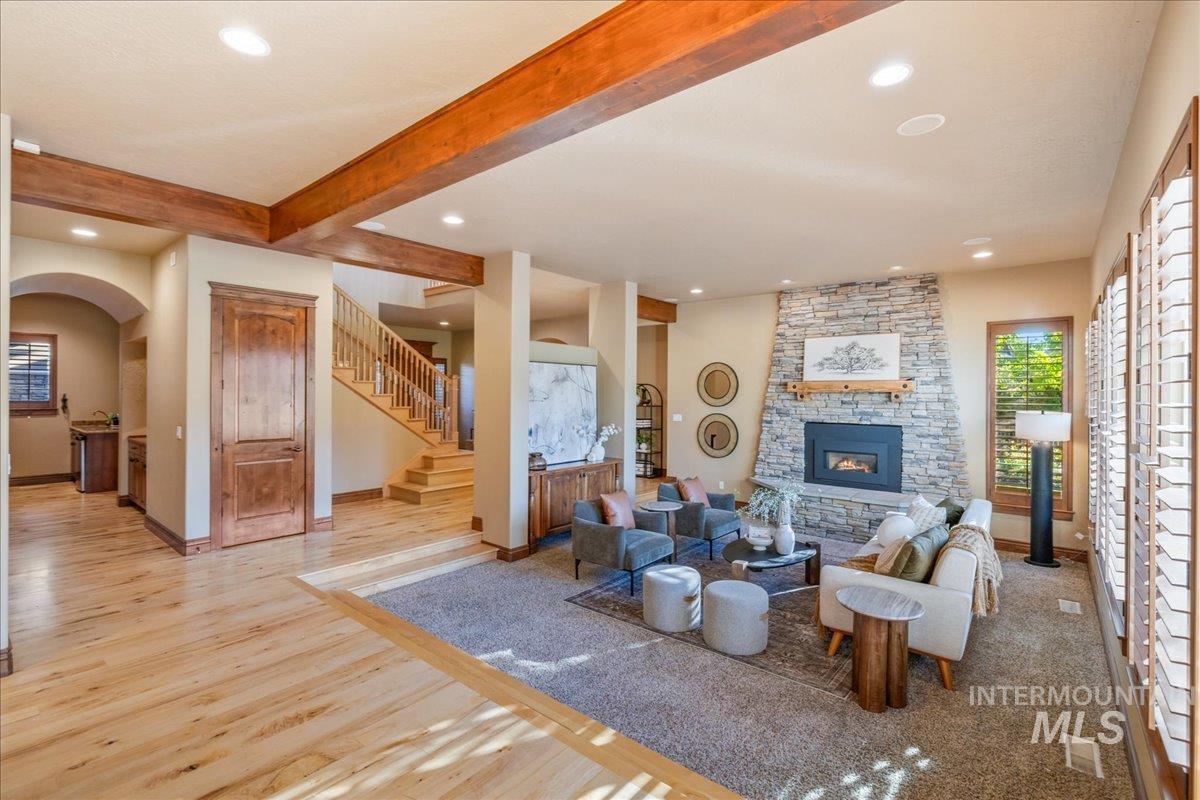 1479 West Oakhampton Drive Eagle, ID 83616 - Photo 18 of 49 Living area featuring beam ceiling, stairway, a fireplace, wood finished floors, and arched walkways