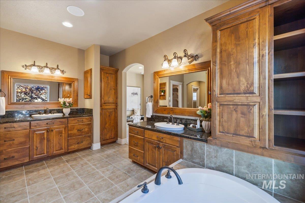 1479 West Oakhampton Drive Eagle, ID 83616 - Photo 33 of 49 Bathroom featuring two vanities, light tile patterned flooring, a garden tub, and recessed lighting