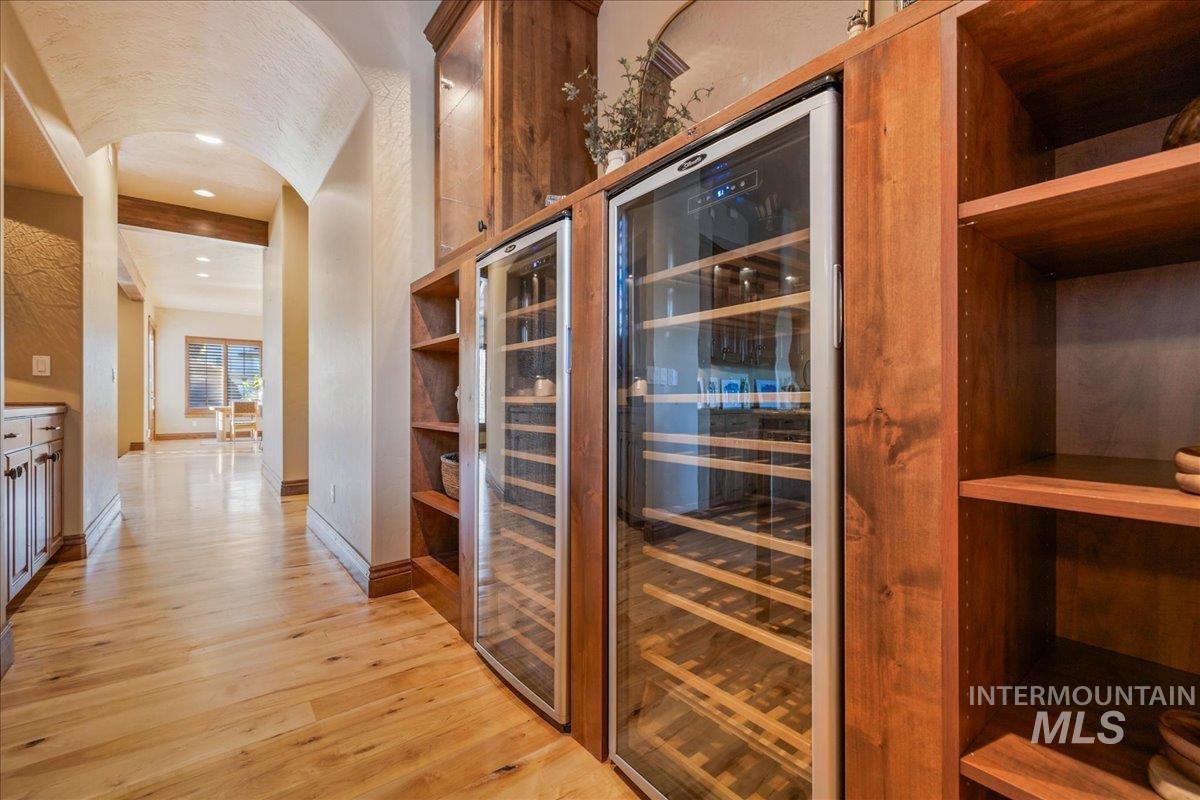 1479 West Oakhampton Drive Eagle, ID 83616 - Photo 8 of 49 Wine area featuring light wood-style flooring, arched walkways, beverage cooler, and recessed lighting