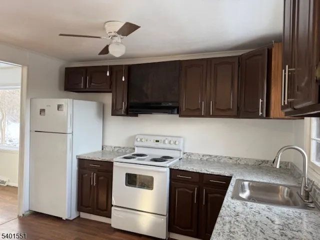 a kitchen with stainless steel appliances granite countertop a stove a refrigerator and a sink with wooden cabinets