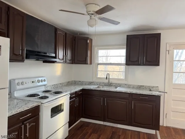 a kitchen with granite countertop a sink a stove a microwave and wooden cabinets