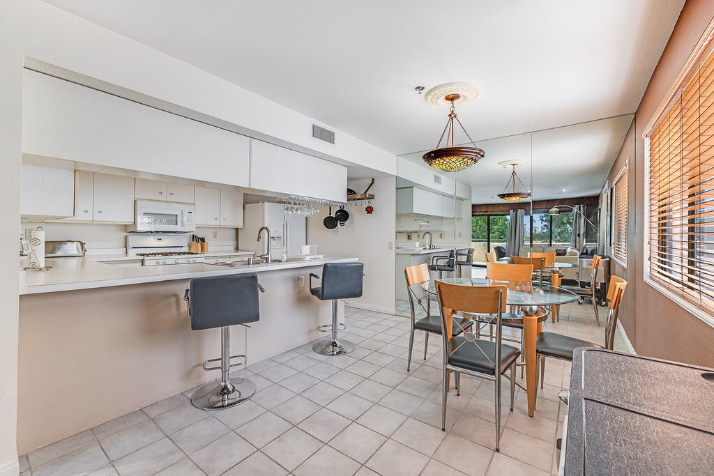 200 East Racquet Club Road, Unit 68 Palm Springs, CA 92262 - Photo 11 of 32 a kitchen with a dining table chairs stainless steel appliances and cabinets