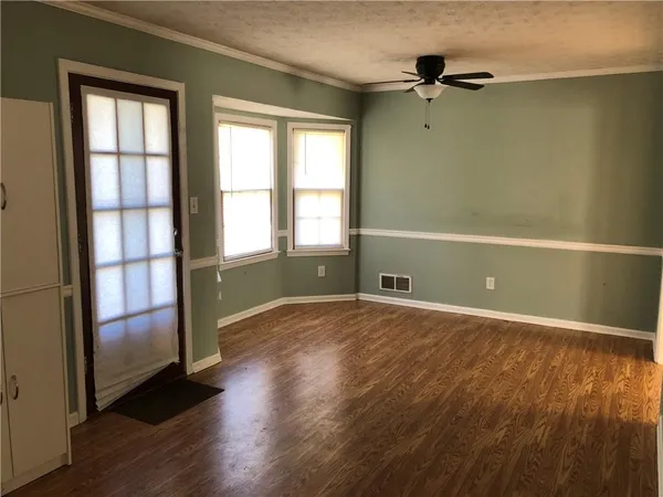 an empty room with wooden floor and windows