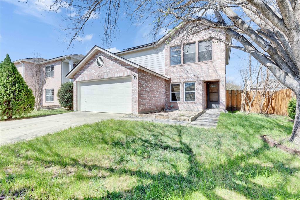 The property features a brick facade, an attached garage, a driveway, and a front yard with mature trees