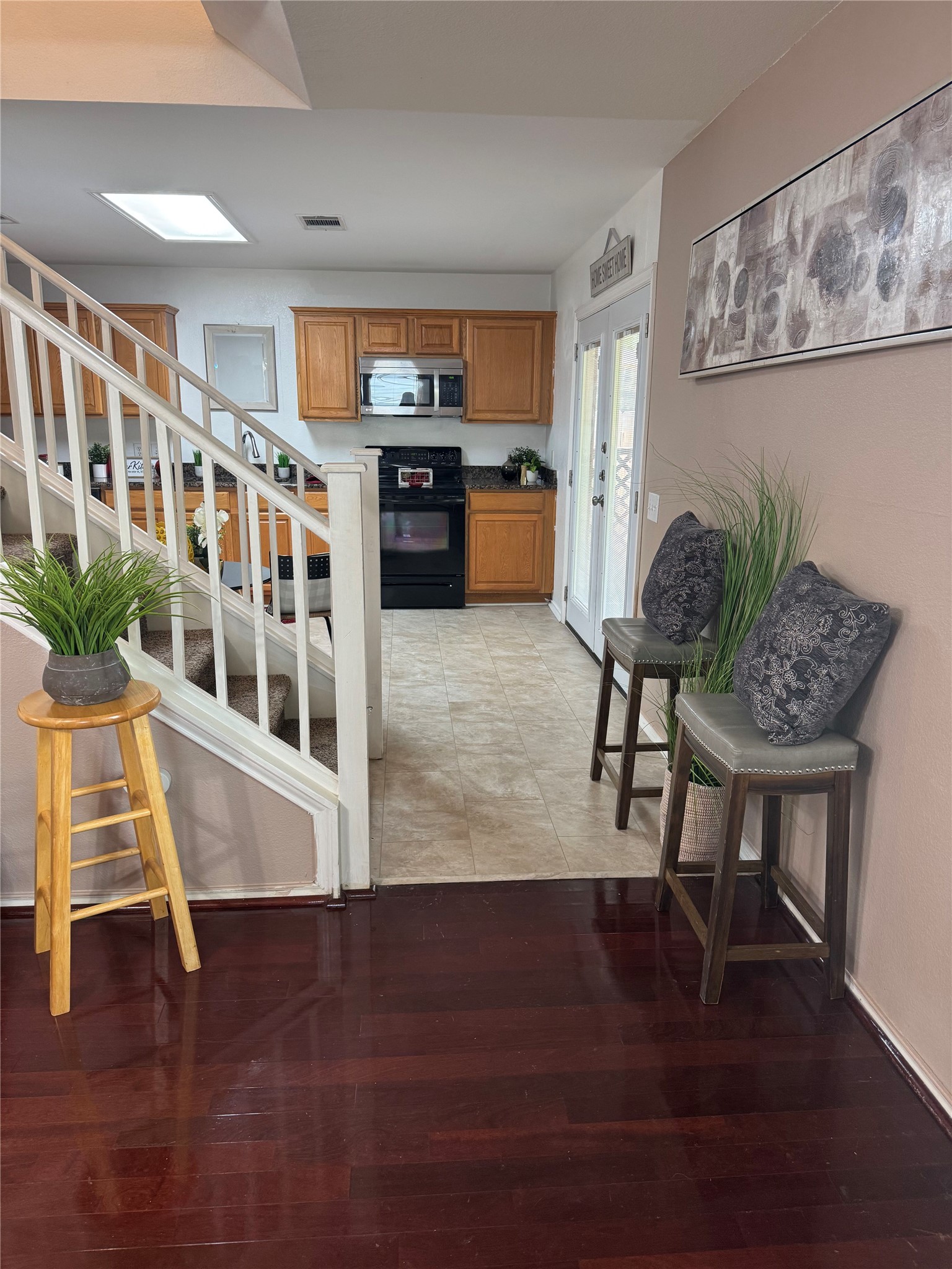 7504 Redrick Drive Austin, TX 78747 - Photo 14 of 34 Rich wood-finish flooring extending into the foreground, complemented by a white staircase with wood railings