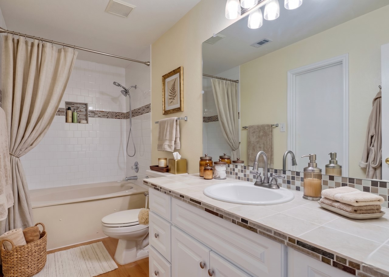 7504 Redrick Drive Austin, TX 78747 - Photo 21 of 34 Bathroom featuring a white vanity with a tiled countertop, an integrated sink with a chrome faucet, and a large mirror