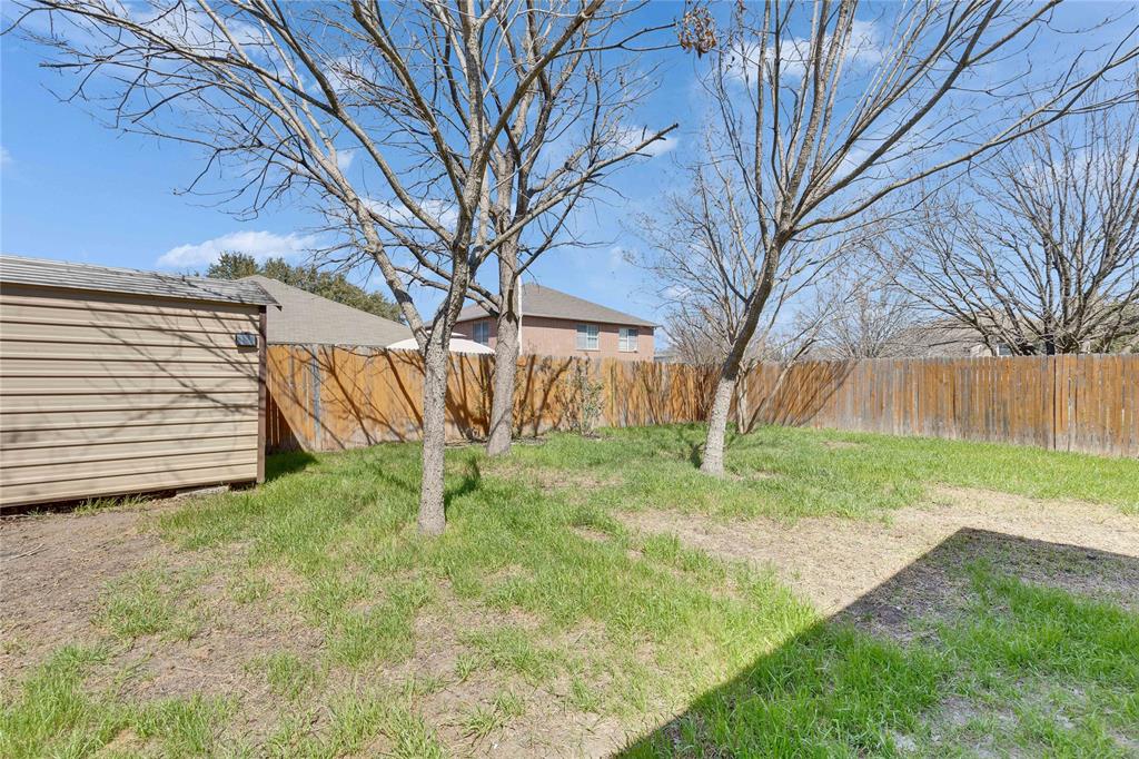 7504 Redrick Drive Austin, TX 78747 - Photo 32 of 34 The property features a spacious yard with a wooden privacy fence, a storage shed, and several mature trees