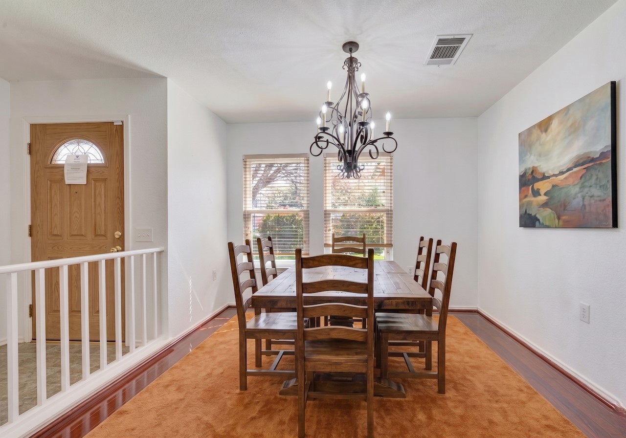 7504 Redrick Drive Austin, TX 78747 - Photo 5 of 34 Dining area featuring hardwood floors, a wrought iron chandelier, and two windows with blinds