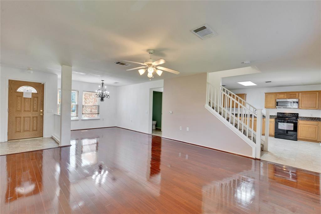 7504 Redrick Drive Austin, TX 78747 - Photo 6 of 34 The property features an open living area with polished wood flooring, a ceiling fan, and a view into the kitchen, which includes wood cabinetry, a black range, and a skylight