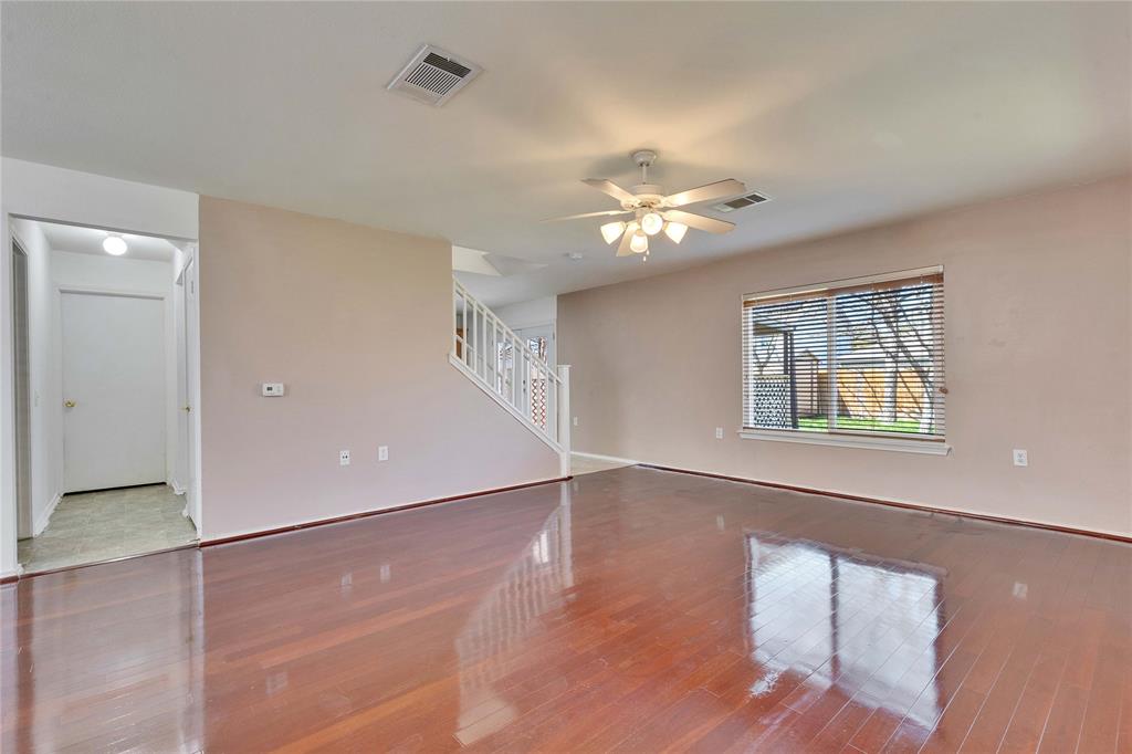 7504 Redrick Drive Austin, TX 78747 - Photo 8 of 34 Spacious living area featuring polished wood flooring, a ceiling fan with integrated lighting, and a window with horizontal blinds
