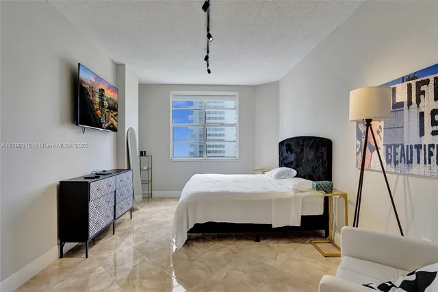 a bedroom with a bed a flat screen tv and dresser