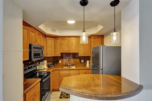 a kitchen with stainless steel appliances granite countertop a sink a stove and a refrigerator