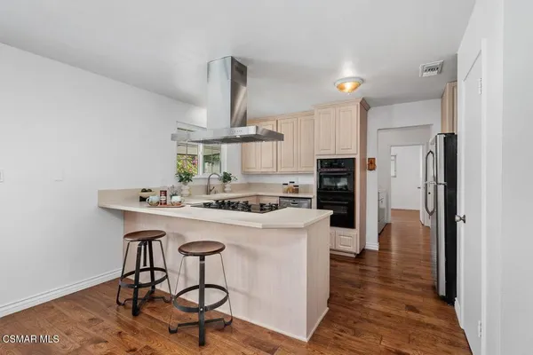 a kitchen with a table chairs a stove and wooden floor
