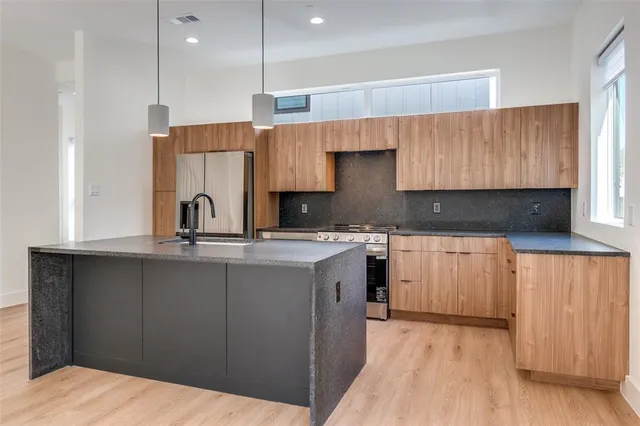 a kitchen with stainless steel appliances a sink a stove a refrigerator and cabinets