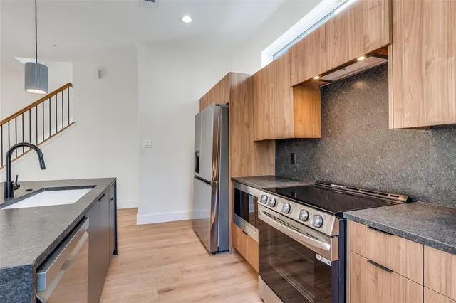 a kitchen with granite countertop a sink a stove and refrigerator