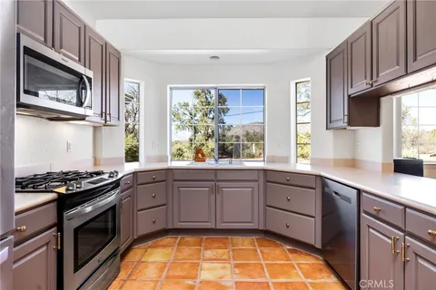 a kitchen with stainless steel appliances granite countertop a stove a sink dishwasher and microwave with wooden floor