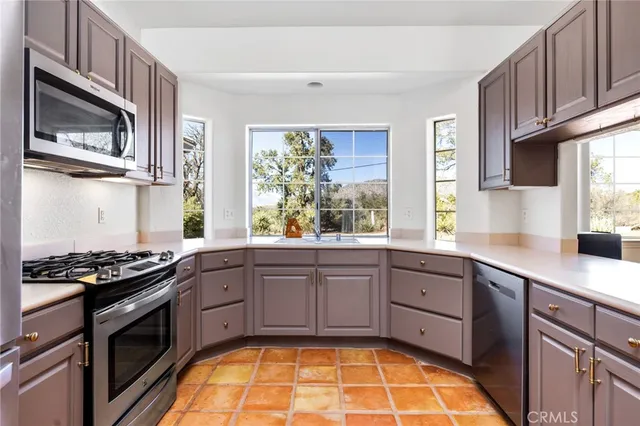 a kitchen with stainless steel appliances granite countertop a stove a sink dishwasher and microwave with wooden floor
