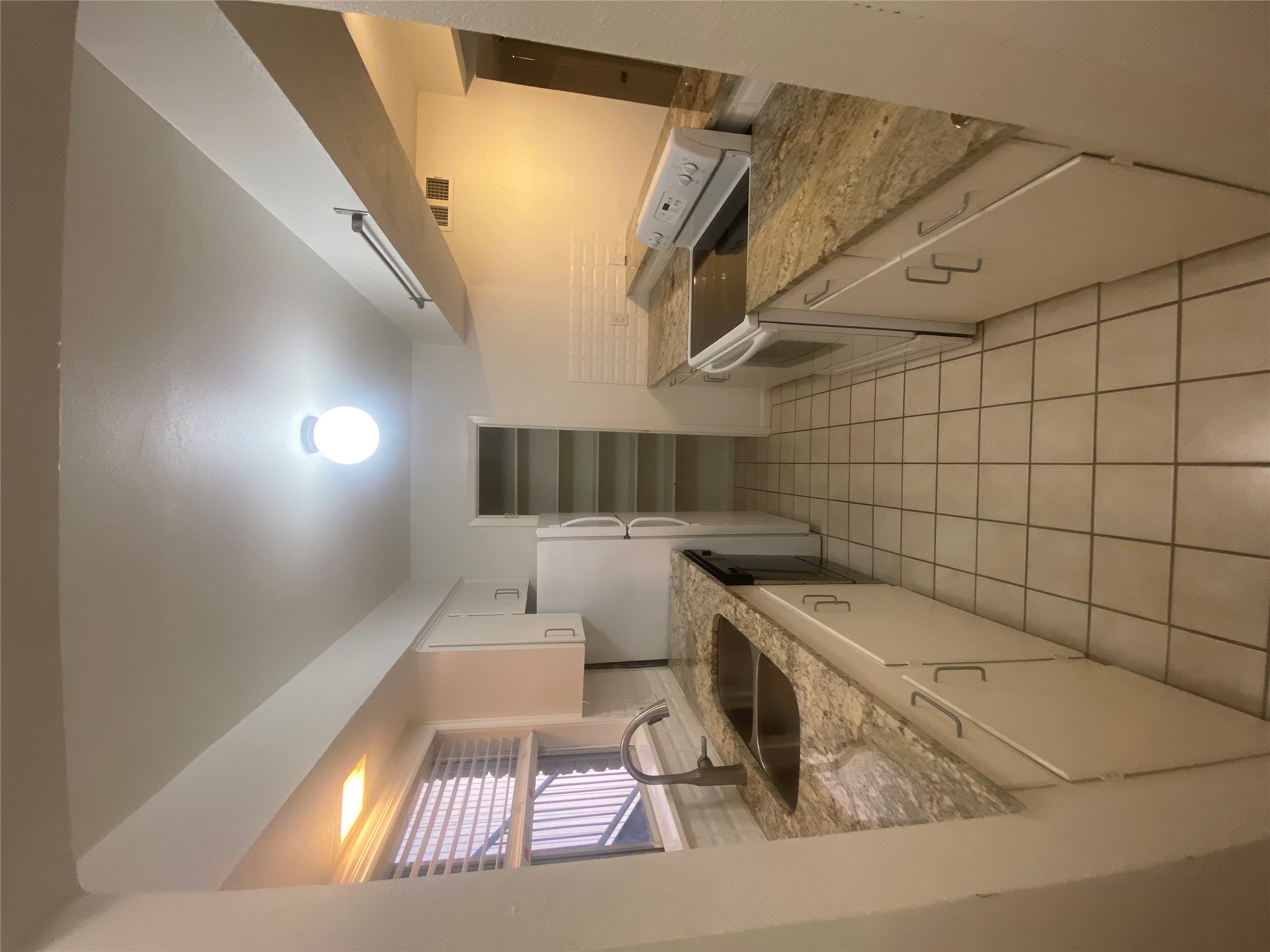 Kitchen with white electric range oven, light stone countertops, white cabinets, light tile patterned floors, and dishwasher