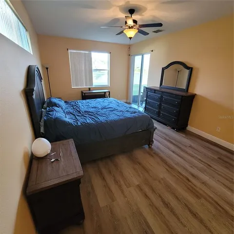 a spacious bedroom with a bed a dresser with wooden floor