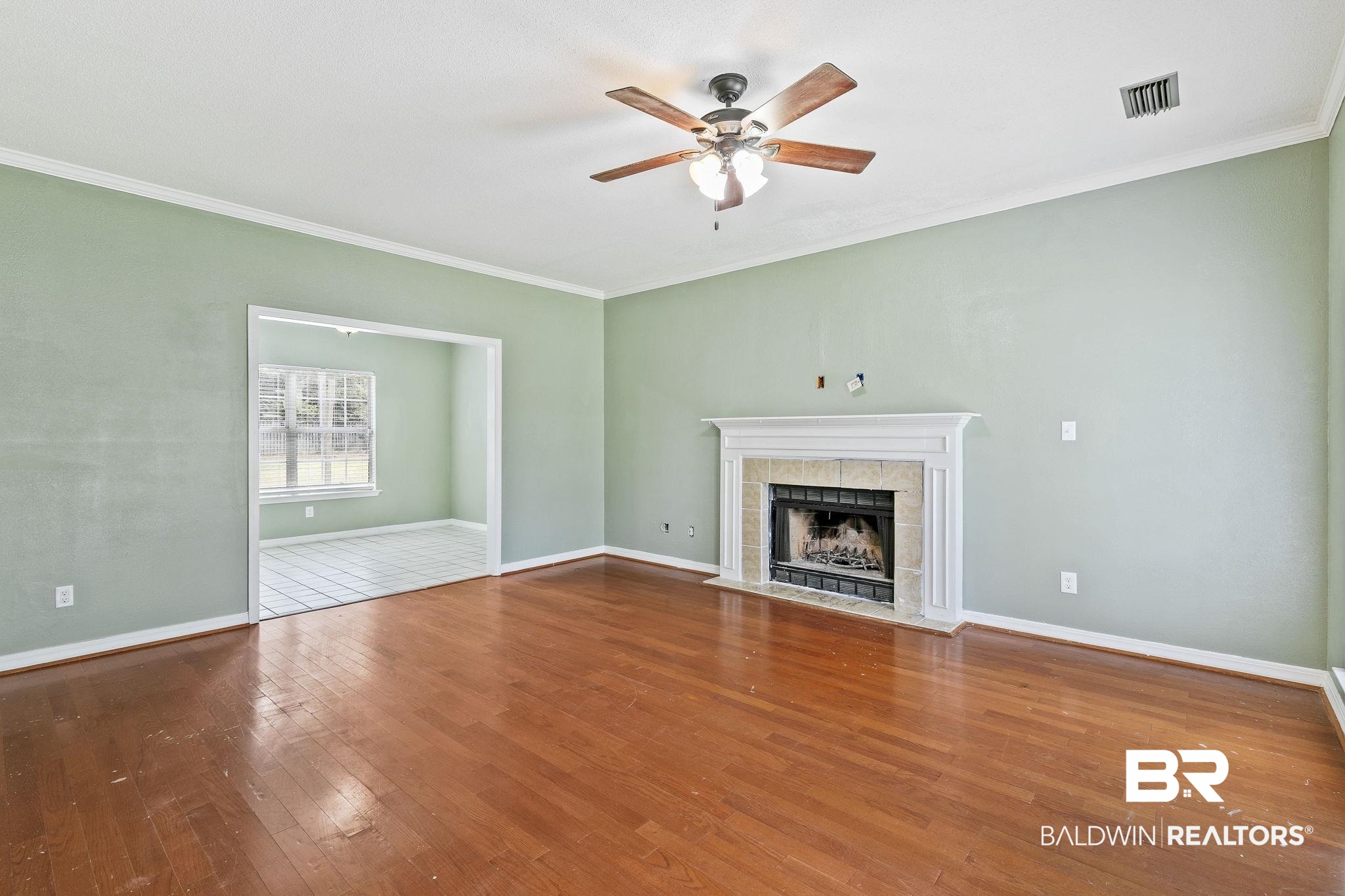 474 Ridgewood Drive Daphne, AL 36526 - Photo 12 of 57 Unfurnished living room with crown molding, wood-type flooring, a tile fireplace, and ceiling fan