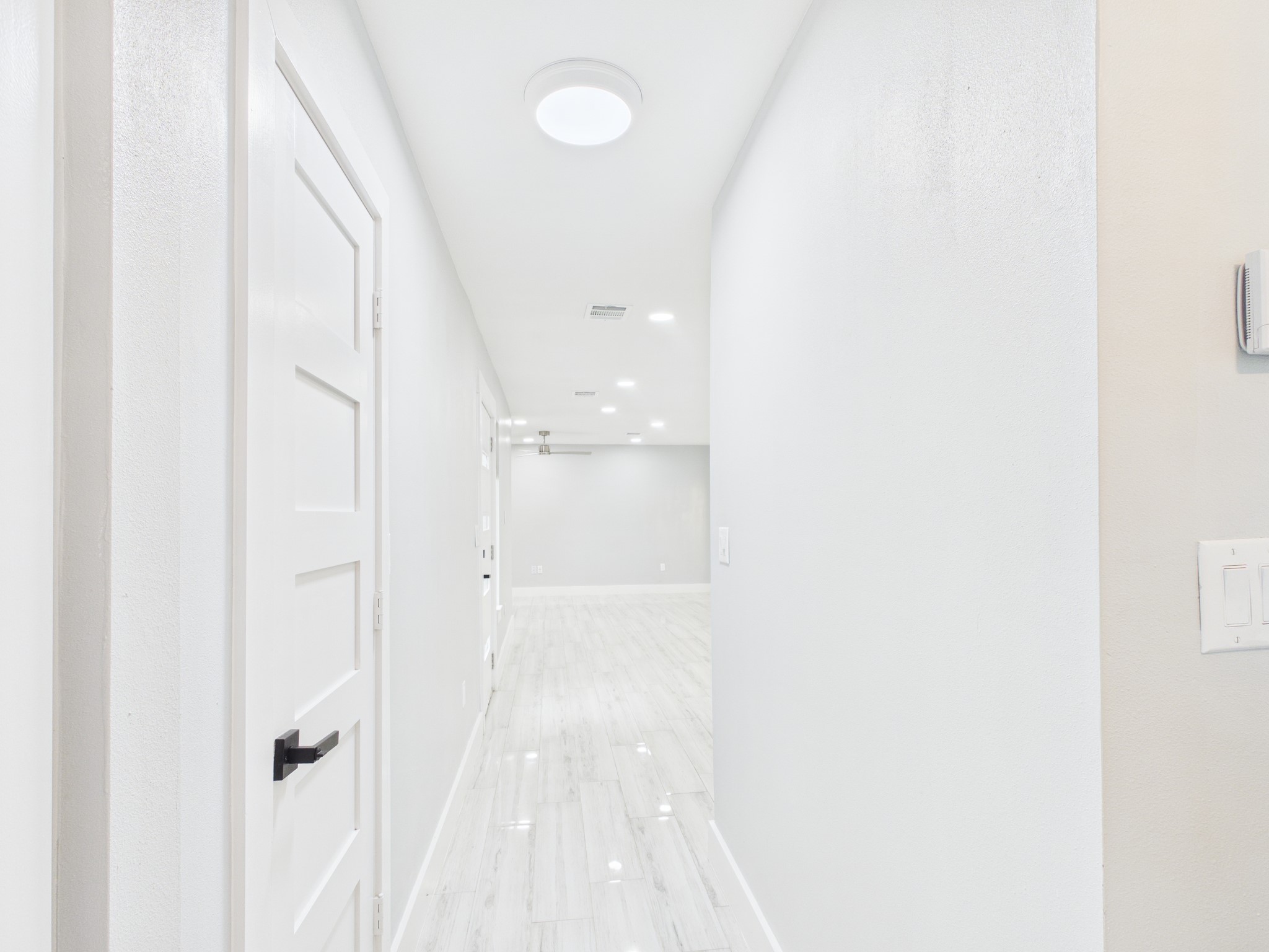 4927 Kelso Street Houston, TX 77021 - Photo 23 of 45 Bright hallway with modern, white walls and sleek flooring, leading to an open living space. Features recessed lighting and contemporary door design.