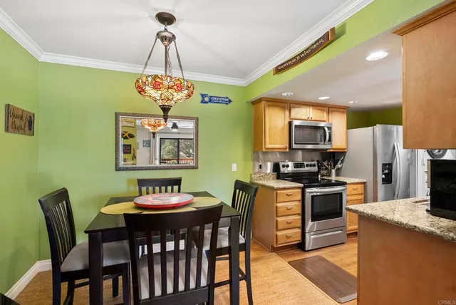a kitchen with stainless steel appliances granite countertop a dining table chairs stove refrigerator and microwave