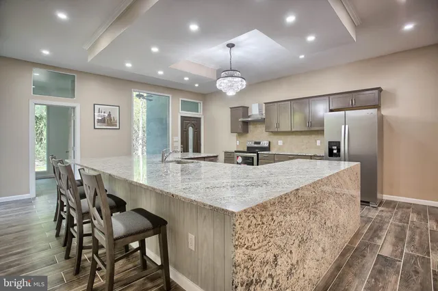 a large kitchen with kitchen island a island a sink stainless steel appliances and cabinets