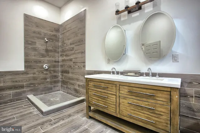 a bathroom with a granite countertop sink a mirror and shower