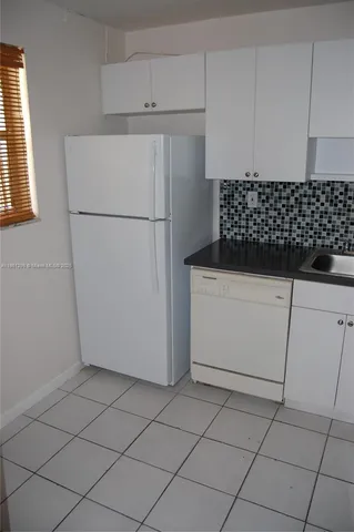 a white refrigerator freezer and a granite counter in a kitchen