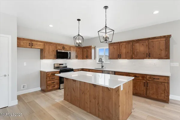 a kitchen with stainless steel appliances granite countertop a sink a stove and a wooden floors