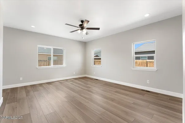 a view of an empty room with a window and wooden floor