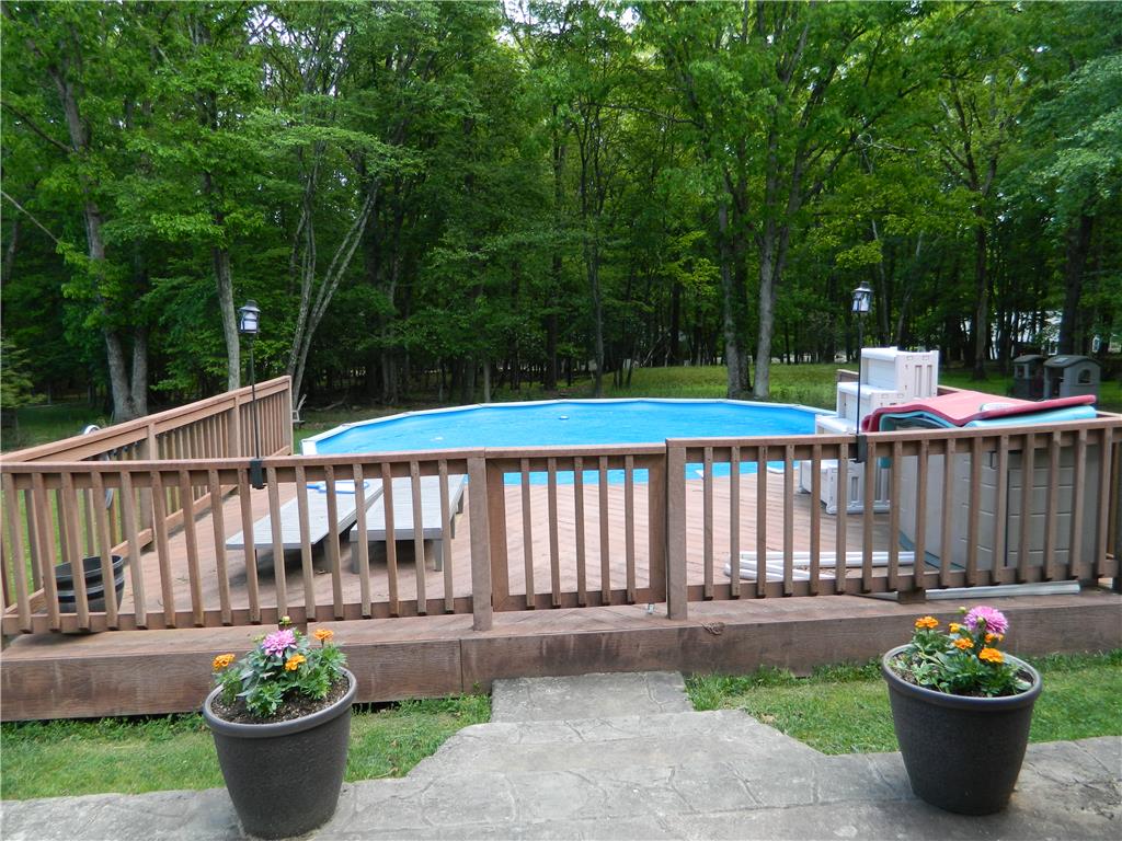328 Pin Oak Road Stroudsburg, PA 18360 - Photo 3 of 37 An inviting pool area awaits, framed by a wooden deck and a lush, verdant backdrop.