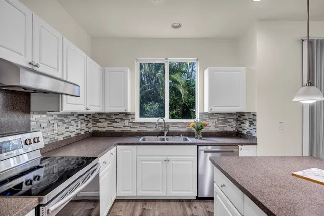 a kitchen with granite countertop a sink a stove and cabinets
