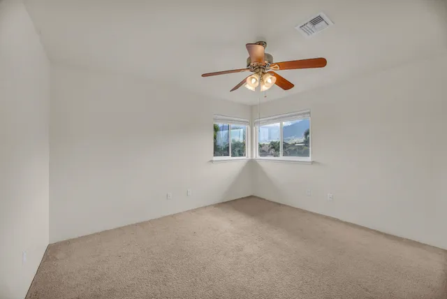an empty room with windows and fan
