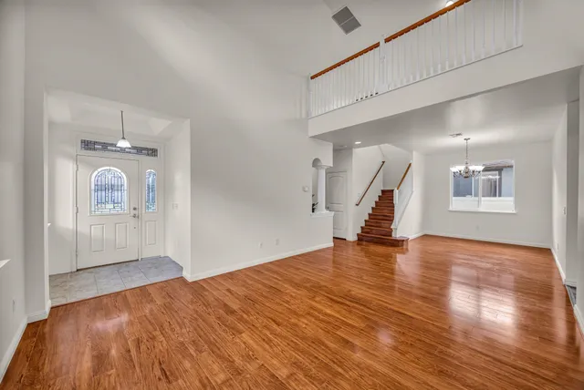 a view of empty room with wooden floor and fan