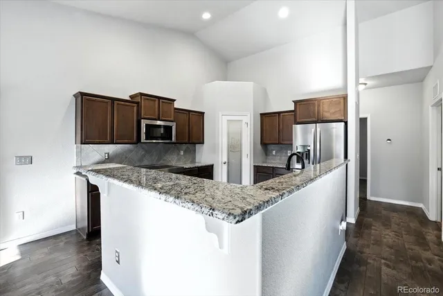 a kitchen with stainless steel appliances granite countertop a sink and a refrigerator