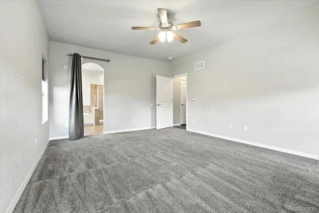 a view of a big room with windows and chandelier fan