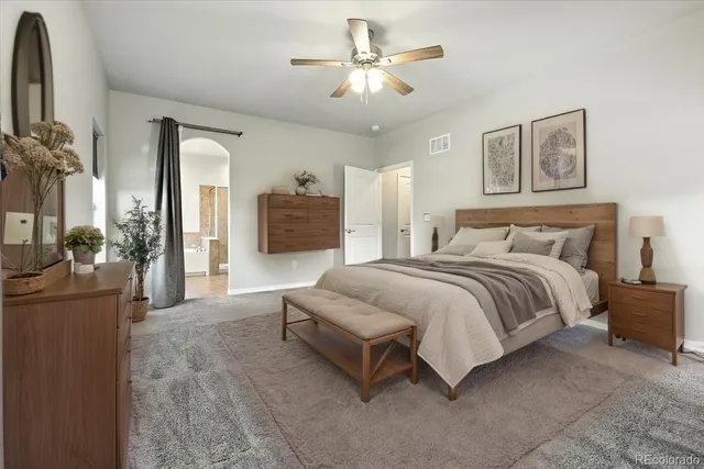 a spacious bedroom with a bed a couch and a chandelier