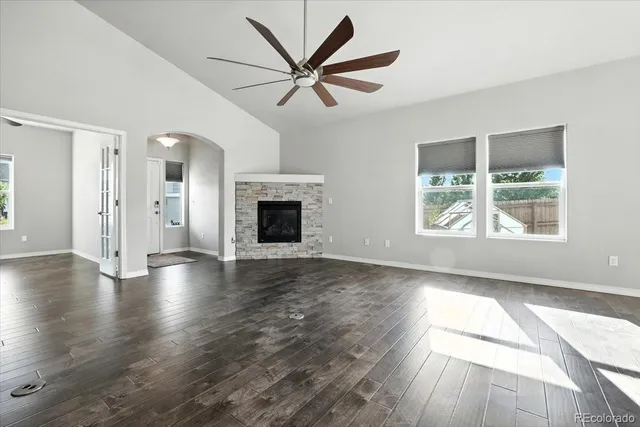 an empty room with wooden floor a ceiling fan and windows