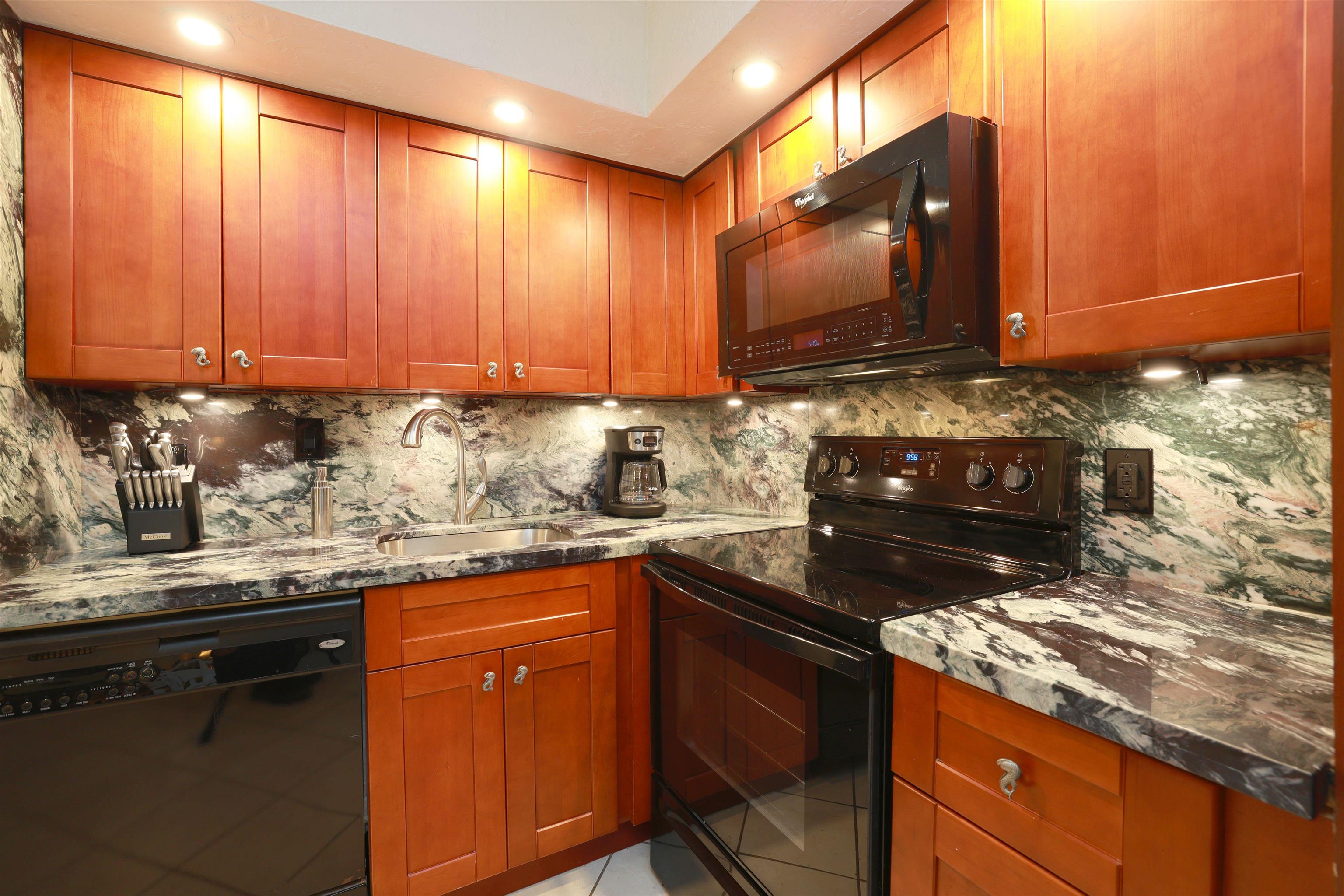 3543 Lower Honoapiilani Road, Unit C107 Lahaina, HI 96761 - Photo 25 of 49 a kitchen with granite countertop wooden cabinets and a stove top oven