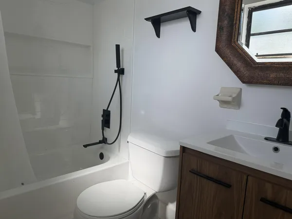 a bathroom with a granite countertop sink a toilet and shower