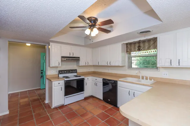a kitchen with stainless steel appliances a stove a sink cabinets and a window