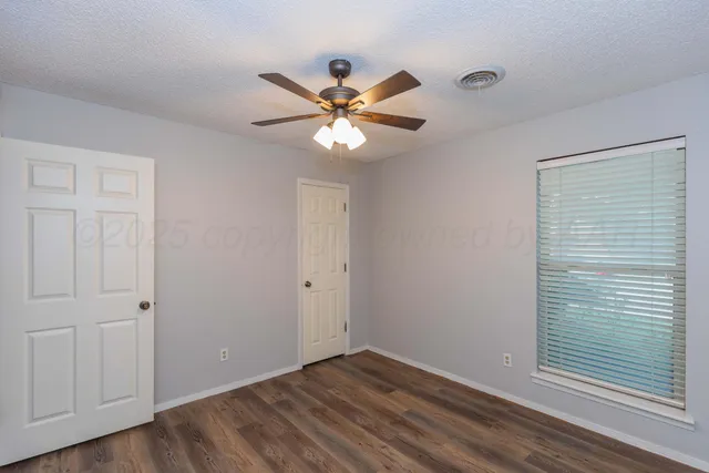 a view of an empty room with a window and a fan