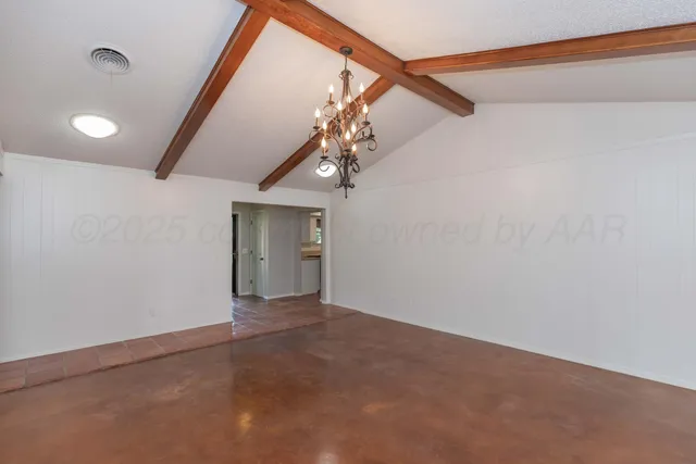 a view of an empty room with a chandelier fan