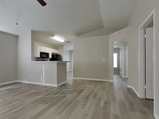a view of a kitchen with an empty room and wooden floor