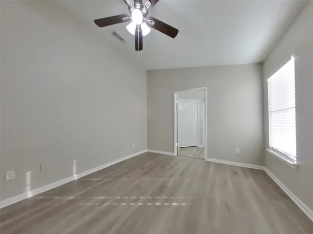 an empty room with windows and fan