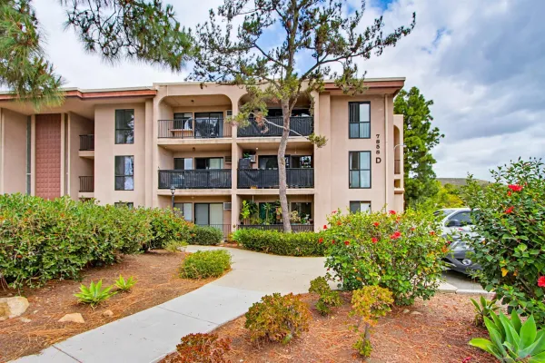 a front view of a multi story residential apartment building with a yard and large trees