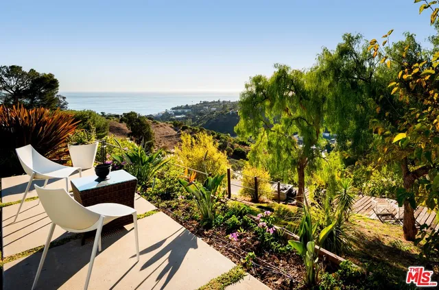 a roof deck with table and chairs and potted plants