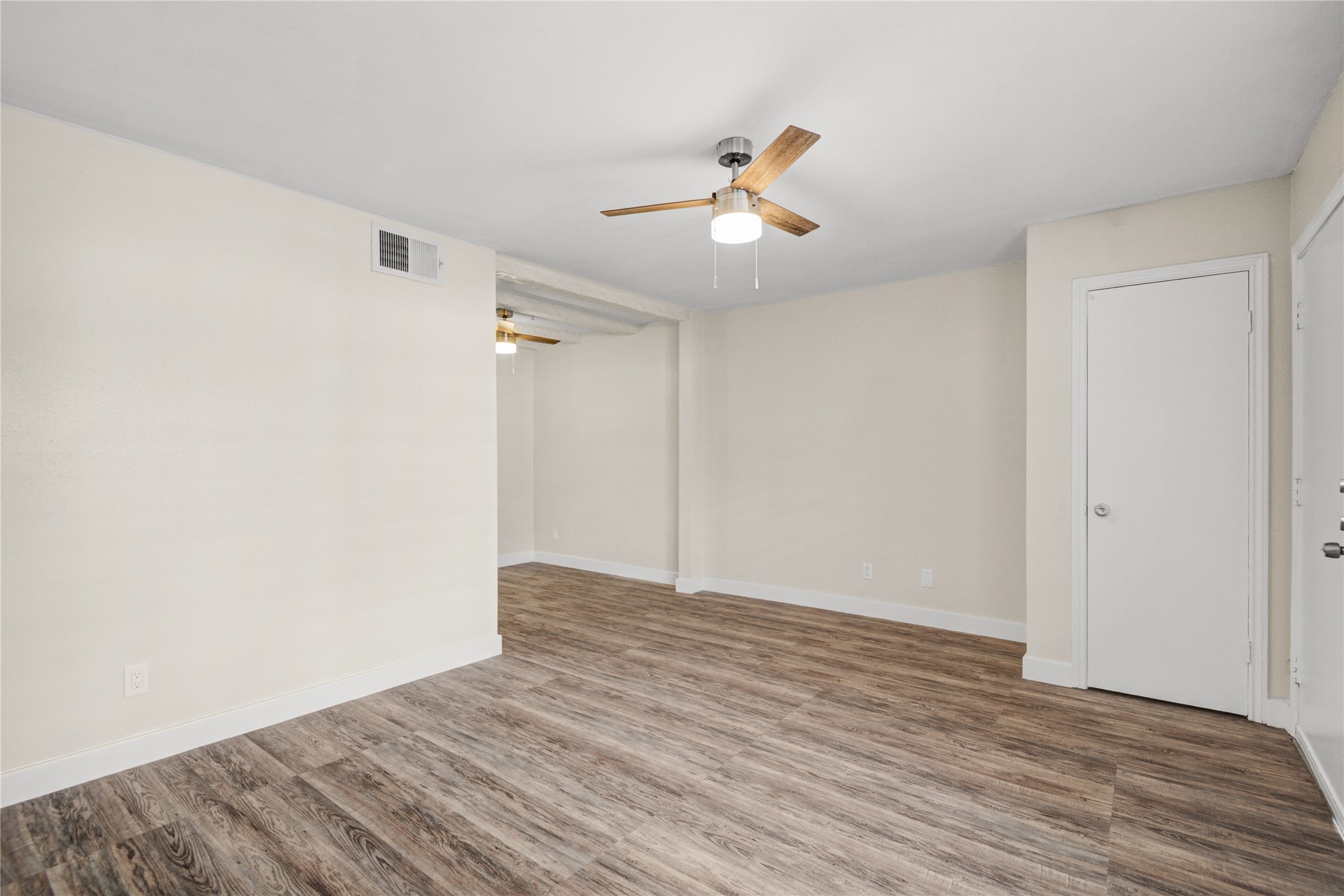 11540 Chimney Rock Road, Unit 117 Houston, TX 77035 - Photo 12 of 38 a view of an empty room with wooden floor and a ceiling fan